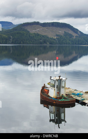 Ein einsamer Schlepper ist ein Pier in ruhigen Gewässern angedockt. Stockfoto