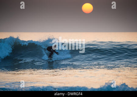 Aberystwyth Wales UK, Mittwoch, 12. März 2014 Surfer fangen die letzten Wellen des Tages bei Sonnenuntergang nach einem weiteren Tag der feine warme sonnige Wetter in Aberystwyth auf der West-Wales Küste UK. Die anhaltende Zauber des warmen Wetters ständiger führte bei Temperaturen bis zu 15C am Nachmittag. Bildnachweis: Keith Morris/Alamy Live-Nachrichten Stockfoto