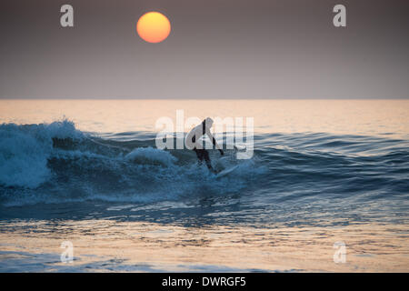 Aberystwyth Wales UK, Mittwoch, 12. März 2014 Surfer fangen die letzten Wellen des Tages bei Sonnenuntergang nach einem weiteren Tag der feine warme sonnige Wetter in Aberystwyth auf der West-Wales Küste UK. Die anhaltende Zauber des warmen Wetters ständiger führte bei Temperaturen bis zu 15C am Nachmittag. Bildnachweis: Keith Morris/Alamy Live-Nachrichten Stockfoto