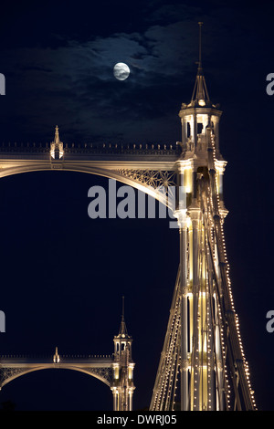 Albert Bridge über die Themse in London, mit Lichtern und der Mond scheint durch den Nachthimmel hinter geschmückt. Stockfoto