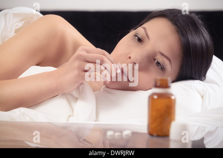 Junge Frau in ihrem Bett, die Einnahme von Medikamenten in Form einer Tablette Stockfoto
