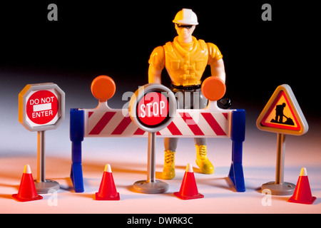 Straße Reparaturen - Spielzeug Arbeiter mit Verkehrszeichen, Zapfen und Barriere. Stockfoto