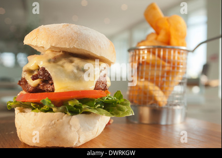 Klassische Beefburger mit Salat, Speck und Käse, serviert mit einer Beilage des französischen gebratenen Kartoffeln oder Pommes Frites. Stockfoto