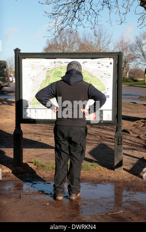 Mann in einer lustigen Pose während des Lesens Parkplan im Richmond Park, London, UK. Stockfoto