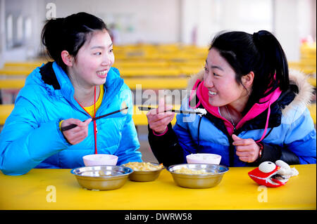 Shenyang. 13. März 2014. Freiwillige Lehrer Jian Zhu (L) und Wang Ninghui, beide Junioren-Studenten der Sporthochschule Shenyang, haben Abendessen an Xiaochengzi neunjährigen Education School of Kangping County in Shenyang, Hauptstadt des nordöstlichen Chinas Liaoning Provinz. Rund 90 junior-Studenten aus Shenyang Sporthochschule wurden an Grund- und Mittelschulen in den Vororten von Shenyang als freiwillige Tearchers für ein halbes Jahr gesendet. © Zhang Wenkui/Xinhua/Alamy Live-Nachrichten Stockfoto