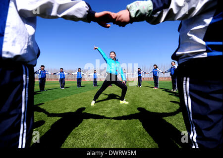 Shenyang. 13. März 2014. Freiwilliger Lehrer Jian Zhu, junior Student der Shenyang Sporthochschule, gibt eine PE-Klasse, Schüler in Xiaochengzi neun Jahre Ausbildung Schule Kangping County in Shenyang, Hauptstadt des nordöstlichen Chinas Liaoning Provinz. Rund 90 junior-Studenten aus Shenyang Sporthochschule wurden an Grund- und Mittelschulen in den Vororten von Shenyang als freiwillige Tearchers für ein halbes Jahr gesendet. © Zhang Wenkui/Xinhua/Alamy Live-Nachrichten Stockfoto