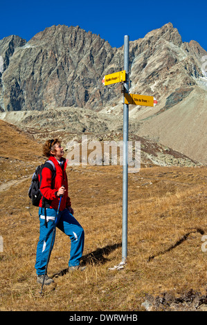 Wanderer auf einem Richtungsanzeiger vor der Bergkette Aiguilles rouges d ' Arolla, Arolla, Wallis, Schweiz Stockfoto