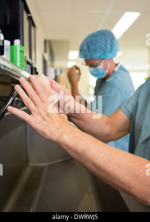 Chirurgen, die Wäsche von Hand mit Kollegen Stockfoto