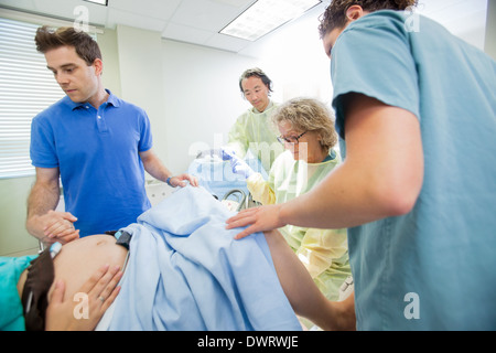 Ärzteteam untersucht schwangere Frau während der Geburt In Betriebsart Stockfoto