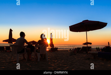 Ein paar sitzt am Strand bei Sonnenuntergang, Strand von Sanur, Bali, Indonesien Stockfoto