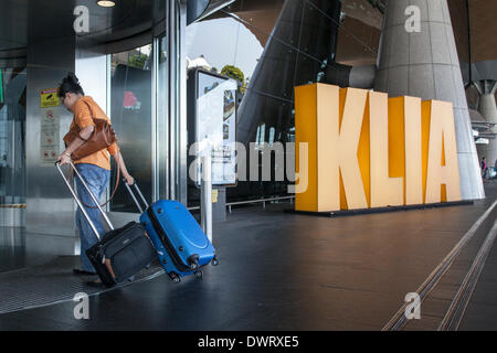 Sepang, Malaysia. 11. März 2014. Ein Reisender geht vorbei an Kuala Lumpur International Airport (KLIA) Schilder, wie sie an den Flughafen Abflughalle in Sepang, Malaysia Kredit ankommt: Asien Datei/Alamy Live News Stockfoto