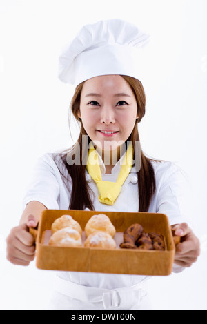 eine weibliche Konditor hält eine Box mit muffins Stockfoto