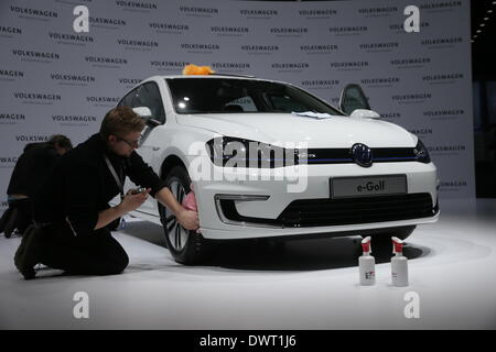 Berlin, Deutschland, 12. März 2014. Ein Mitarbeiter poliert eine E-Golf-Car auf der Jahrespressekonferenz des deutschen Automobilherstellers Volkswagen (VW) auf dem ehemaligen Flughafen Tempelhof in Berlin. Foto: MICHAEL KAPPELER/Dpa/Alamy Live News Stockfoto