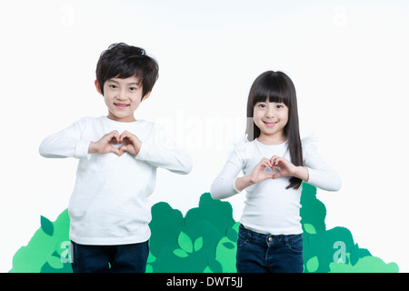 ein Junge und ein Mädchen Herz Schilder herstellen Stockfoto