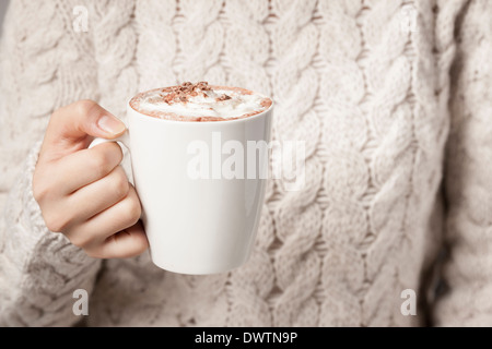 eine Frau, ein warmes Getränk in ihren Händen hält Stockfoto