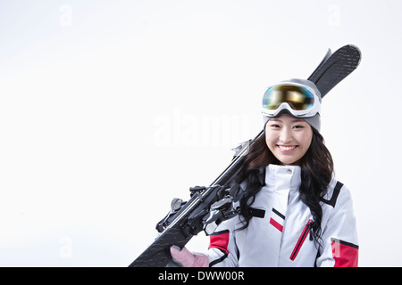 eine Frau hält ein paar Ski Stockfoto