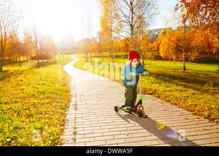 Glückliche drei Jahre alten kleinen Jungen Motorroller im Herbst Park Stockfoto