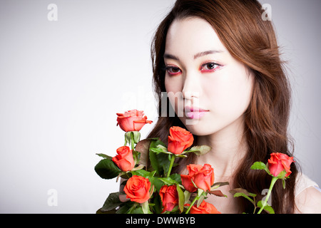 eine Frau mit schweren roten Make-up und Rosen Stockfoto