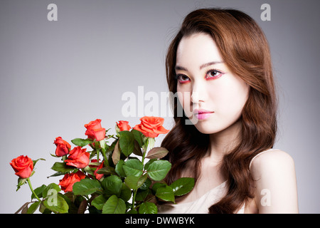 eine Frau mit schweren roten Make-up und Rosen Stockfoto