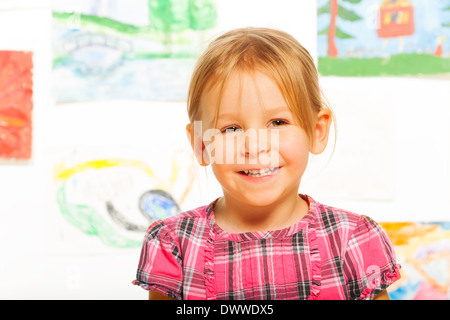 Glücklich lächelnd Porträt der niedliche blonde kleine Mädchen in der Klasse im Kindergarten mit Bildern im Hintergrund schließen Stockfoto