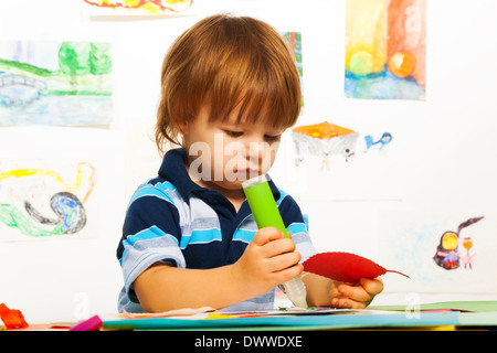 Süße kleine 2 Jahre alt junge in der Kunst kleben Farbe Karton Blatt Stockfoto