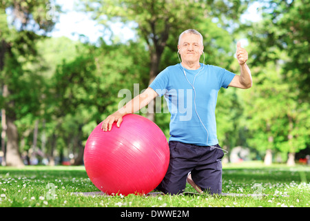 Gesunder Mensch Daumen aufgeben setzte auf eine Gymnastikmatte in einem park Stockfoto