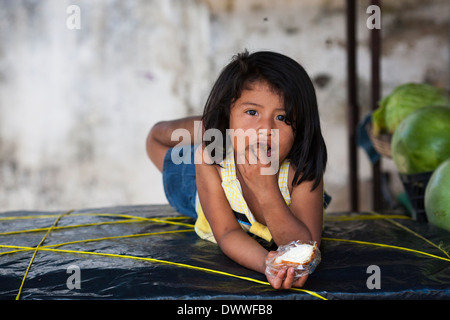 Ein junges Mädchen, ein Kind liegt auf einem Tisch in einem Obststand auf dem Markt der Bergstadt Juayua auf den Rutas de la flores, El Salvador Stockfoto