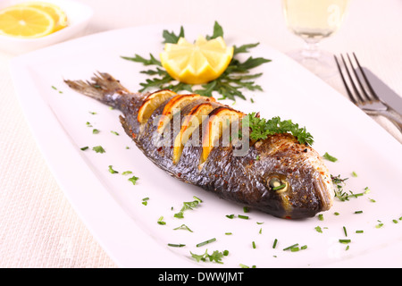 Gegrillte Dorade Fisch, Zitrone, Rucola auf weißen Teller, Nahaufnahme Stockfoto