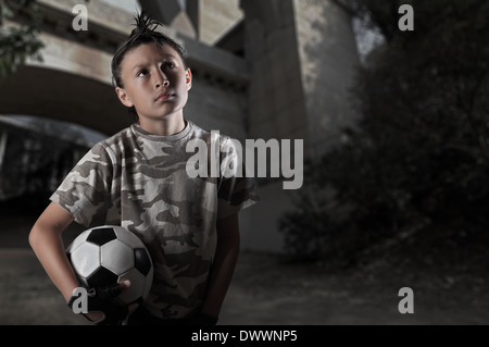 Ein kleiner Junge spielt Streetsoccer Wand Graffiti bedeckt - dramatische Beleuchtung und gedämpften Farben Stockfoto