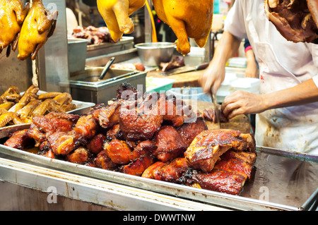 Metzger schneiden gegrilltes Schweinefleisch, auch bekannt als Cha Siu, an einer Hong Kong Fleisch Stand Stockfoto