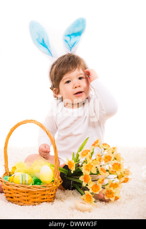 Ester Hase Baby mit Korb mit Eiern und Blüten sitzen auf Teppich Stockfoto