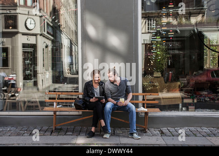 Voller Länge des Paares mit digital-Tablette zusammen auf Bürgersteig Bank Stockfoto