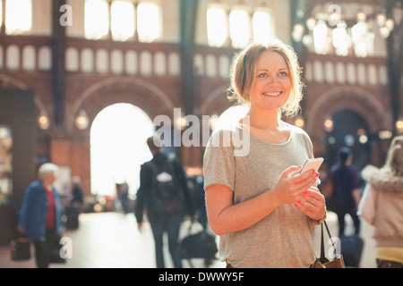 Glücklich Mitte Erwachsene Frau mit Handy stehen am Bahnhof Stockfoto