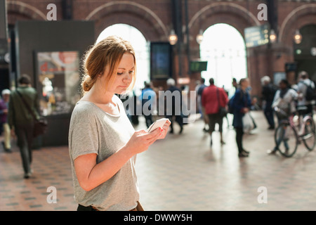 Mitte Erwachsene Frau mit Handy am Bahnhof Stockfoto