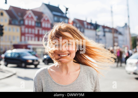 Portrait von glücklich Frau mit windigen Haare auf Stadtstraße Stockfoto