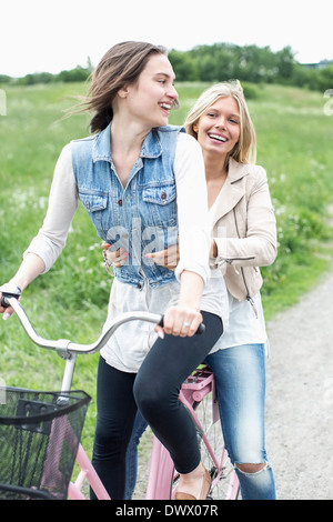 Glückliche Freundinnen genießen Fahrrad fahren auf Landstraße Stockfoto