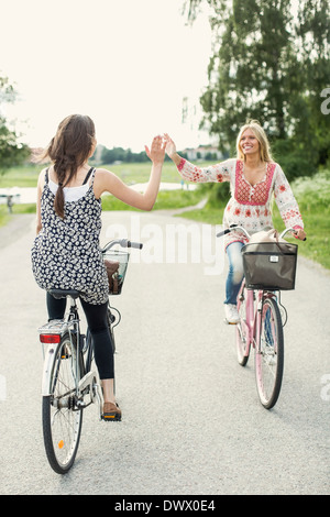 Glücklich Freundinnen geben hohe fünf beim Radfahren auf Landstraße Stockfoto