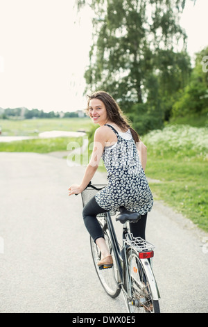 Hintere Ansicht Porträt jungen Frau Radfahren auf Landstraße Stockfoto