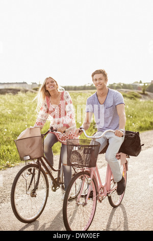 Porträt des jungen Paares Radfahren auf Landstraße Stockfoto