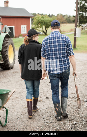 Rückansicht des landwirtschaftlichen paar zu Fuß auf Landstraße Stockfoto