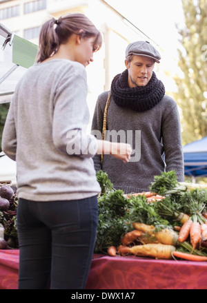 Junger Mann kaufen Gemüse am Marktstand Stockfoto