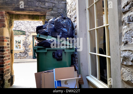 Ein Wheelie bin mit Mülltüten gestapelt an der Spitze in einer Gasse Bakewell Derbyshire England uk Stockfoto