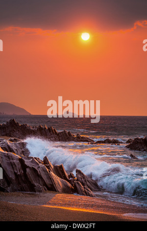 Sonnenaufgang der Wellen auf den Felsen in Slapton Sands, Devon, UK Stockfoto