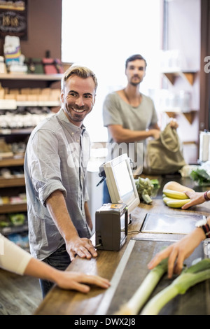 Lächelnder Mann stehend an Supermarkt-Kasse mit Freund im Hintergrund Stockfoto