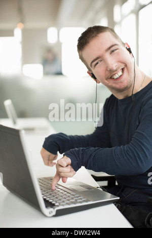 Porträt von glücklich Kaufmann mit zerebraler Lähmung mit Laptop beim Musik hören Stockfoto