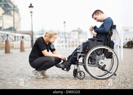 Weibliche Hausmeister auf behinderte Mensch Schuhe auf Straße Stockfoto