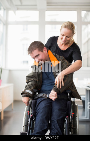 Weibliche Hausmeister unterstützen behinderte Mann im Rollstuhl zu Hause Stockfoto