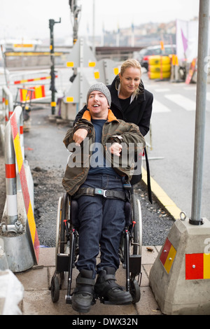 Hausmeister Drücken deaktiviert Mann im Rollstuhl im freien Stockfoto