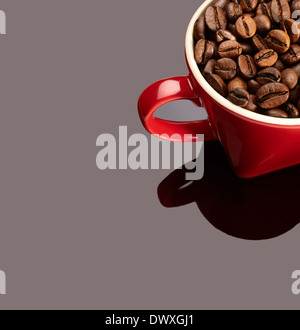 Natürliche Kaffeebohnen auf einem roten Becher auf reflektierte Hintergrund. Stockfoto