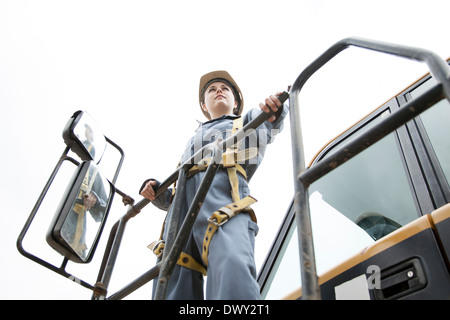 Junge weibliche Industriearbeiter auf Bulldozer stehen Stockfoto